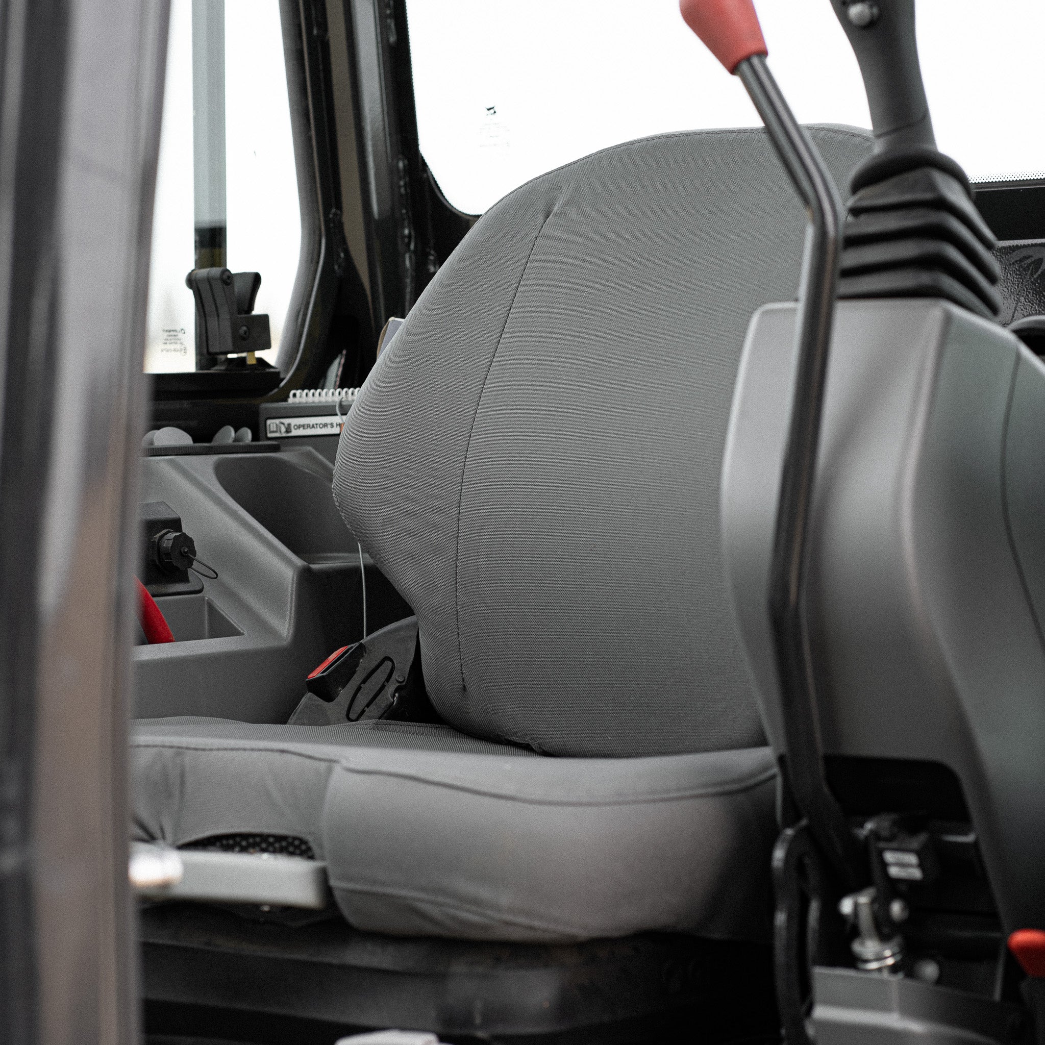 TigerTough Seat Cover E82250 on a Bobcat mini excavator. The seat cover in this picture is gray.