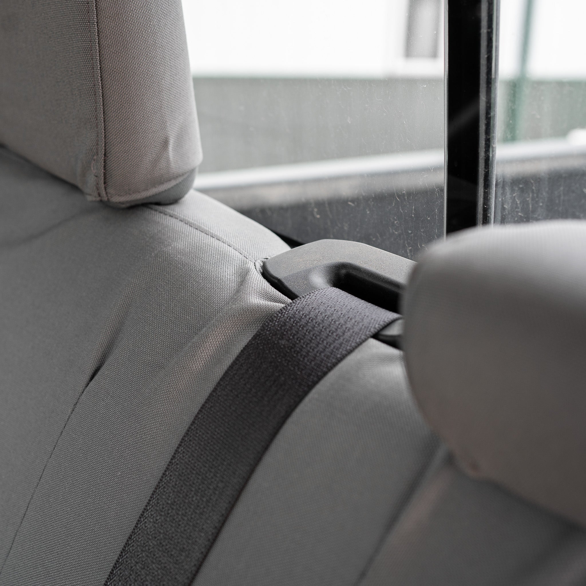 Detail photo showing how the TigerTough seat cover works around the seat belt retractor on the back seat of a RAM truck.