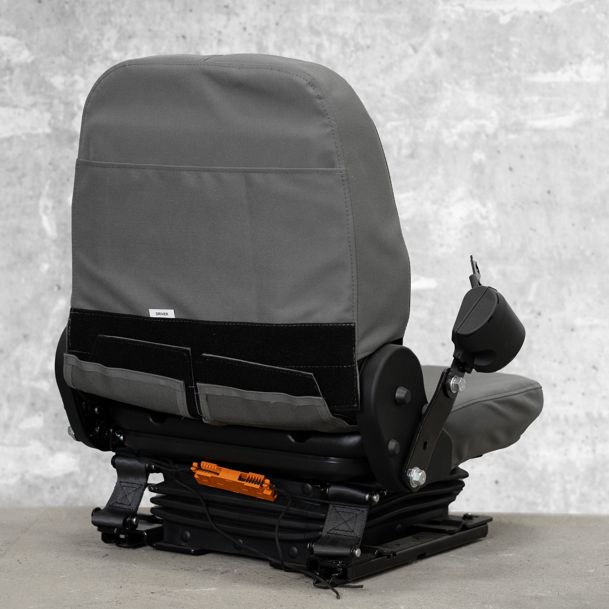 The back view of a heavy equipment seat with TigerTough seat covers on it. This picture shows the StringLock securing the strings behind the seat so you don't have to tie them, and it shows the sturdy hook-and-loop that secures the cover at the back.